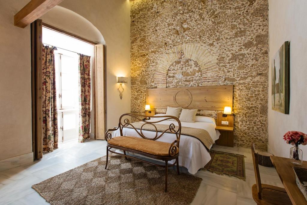 a bedroom with a bed and a bench in a room at Hotel Casa de las Cuatro Torres in Cádiz