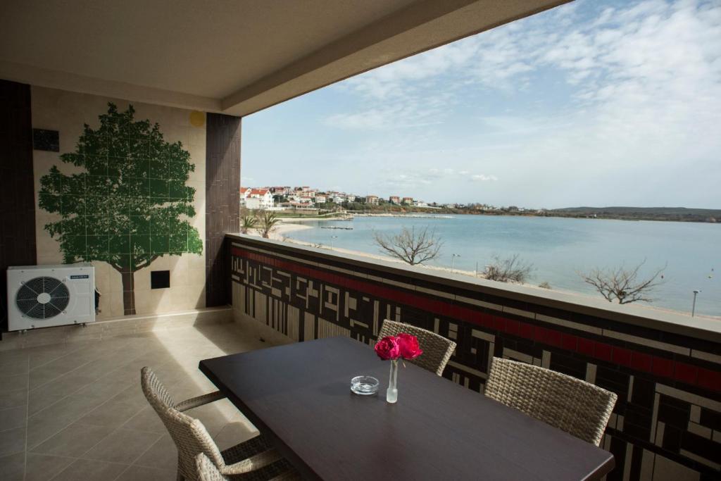 a table and chairs on a balcony with a view of the water at Apartments Svijet Mora in Povljana