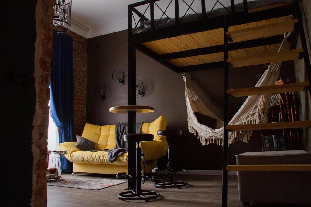 sala de estar con cama elevada y sofá amarillo en Studio Loft on Turgeneva, en Khabarovsk