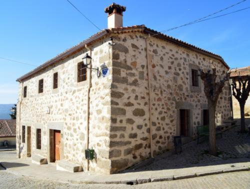 un edificio in pietra con un camino sopra di Casa Rural El Molino I a San Bartolomé de Pinares