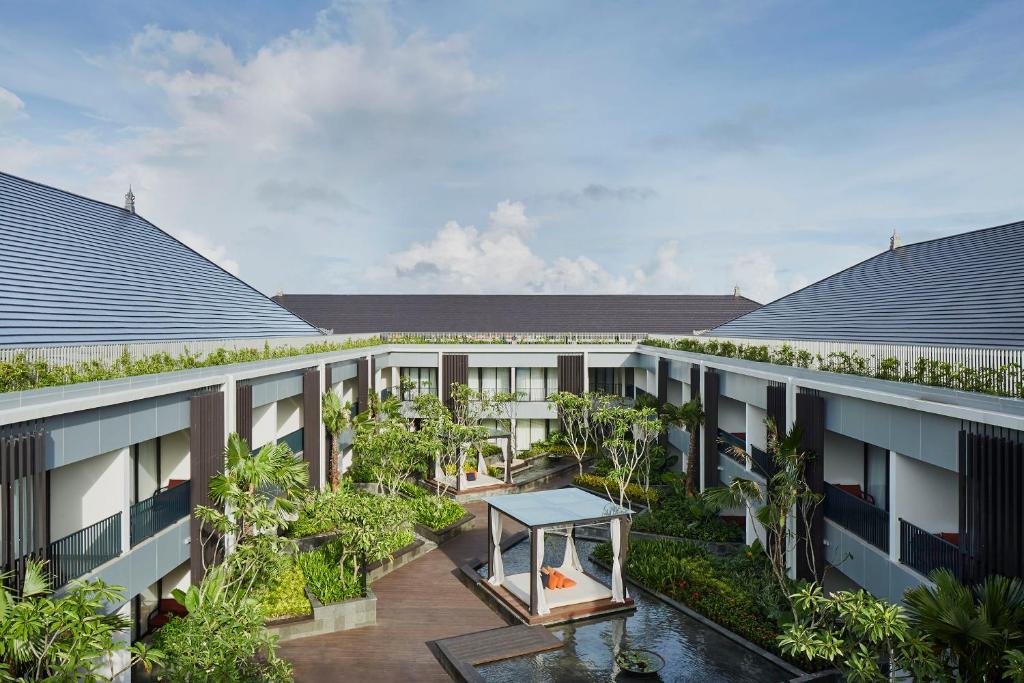 an apartment building with a courtyard with trees at Aryaduta Bali in Kuta