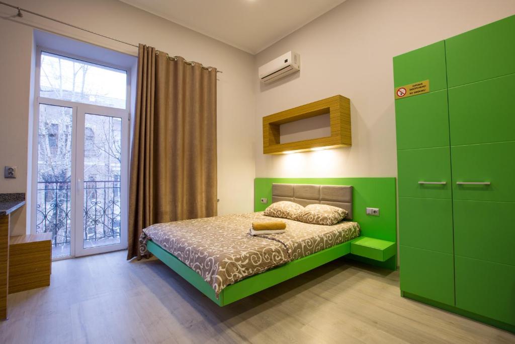 Dormitorio verde con cama y ventana en Pushkinskaya Apartments, en Járkov