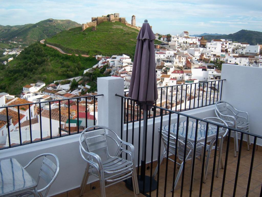 een balkon met een parasol en stoelen en een stad bij Hostal Durán in Alora