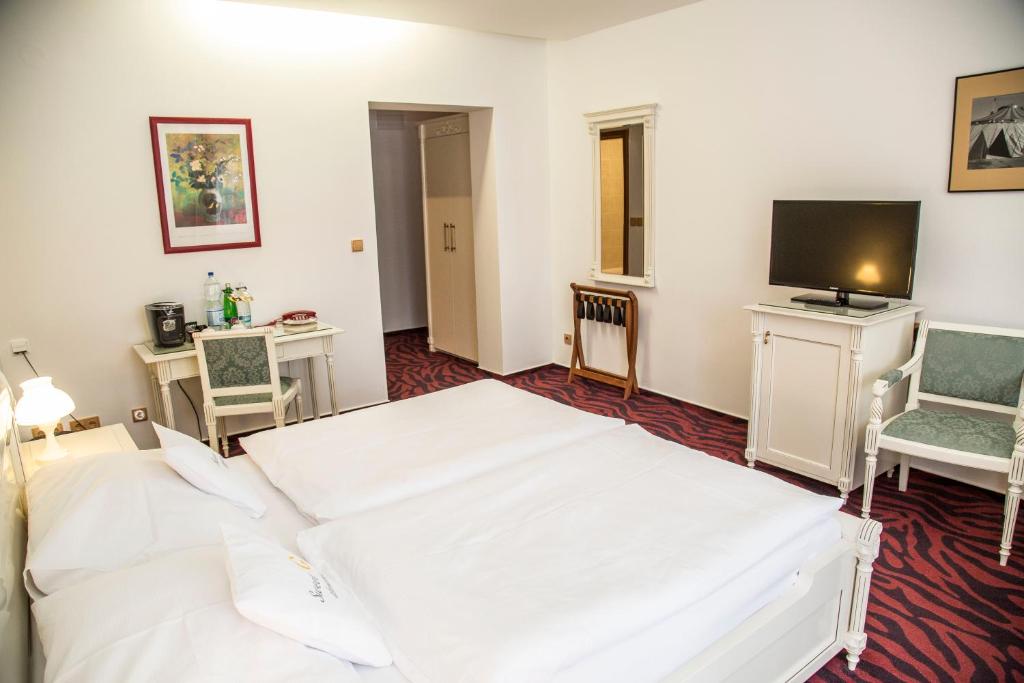 a bedroom with a white bed and a tv at Hotel Galant Lednice in Lednice