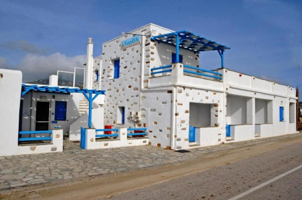 a large white building with blue windows on a road at Tinos Koralli in Tinos Town