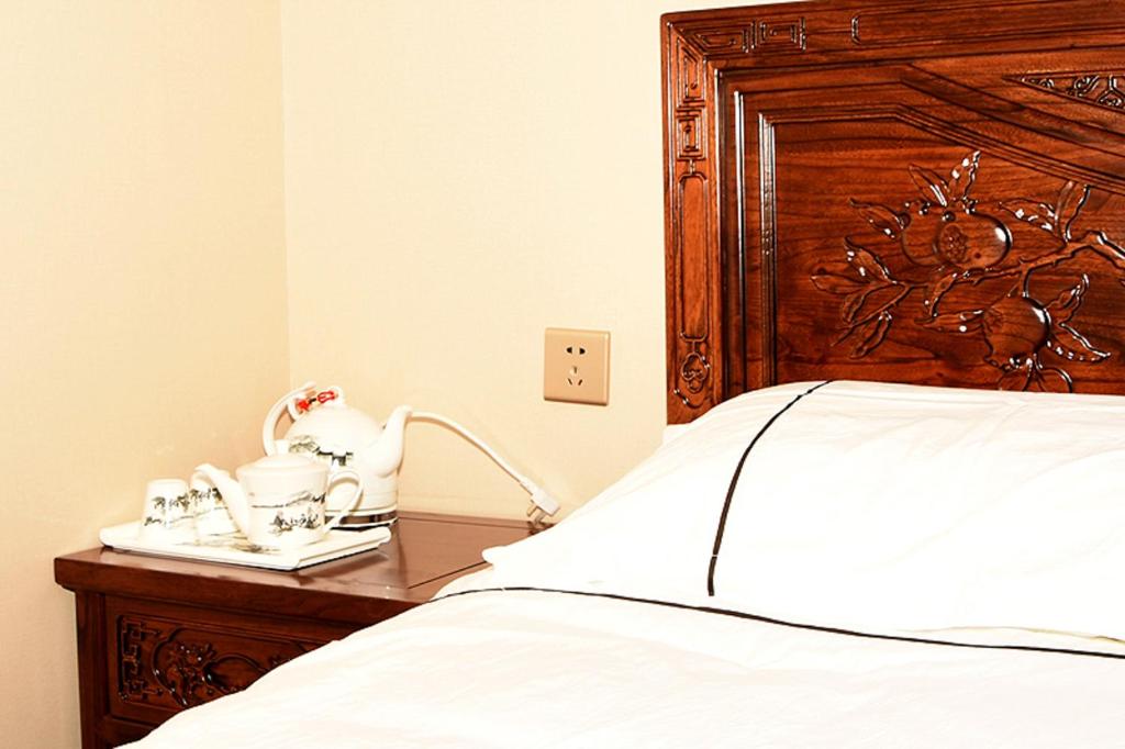 Dong Li Guest House في Miyun: غرفة نوم بسرير من اللوح الخشبي ووقوف ليلي
