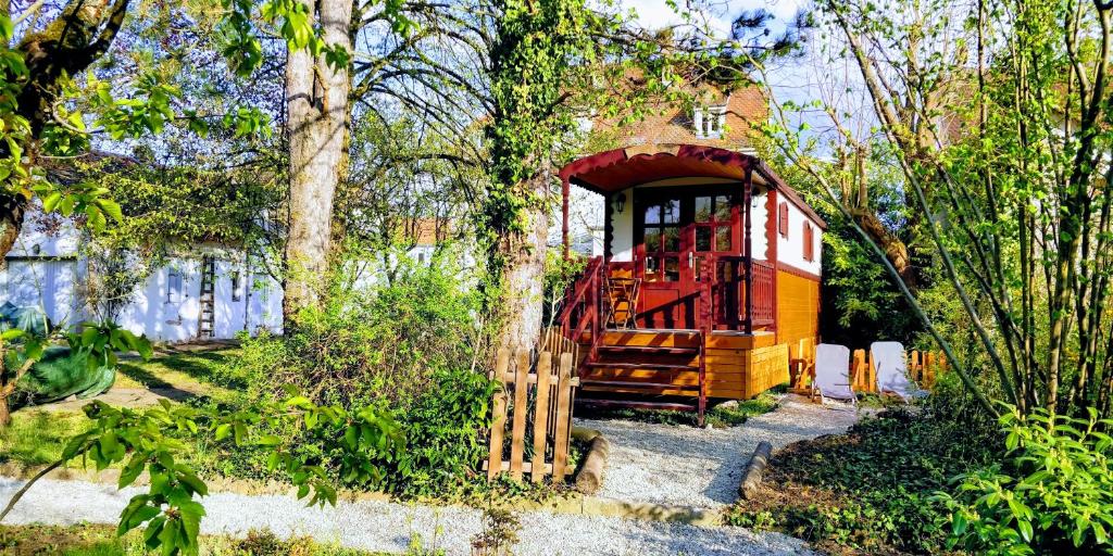 une petite maison rouge et jaune dans un jardin dans l'établissement Roulotte Comtoise à Strasbourg, à Strasbourg