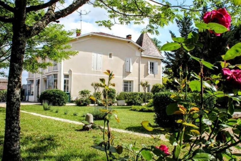 ein großes weißes Haus mit einem Garten mit Rosen in der Unterkunft La chambre d'hotes du Parc in Podensac