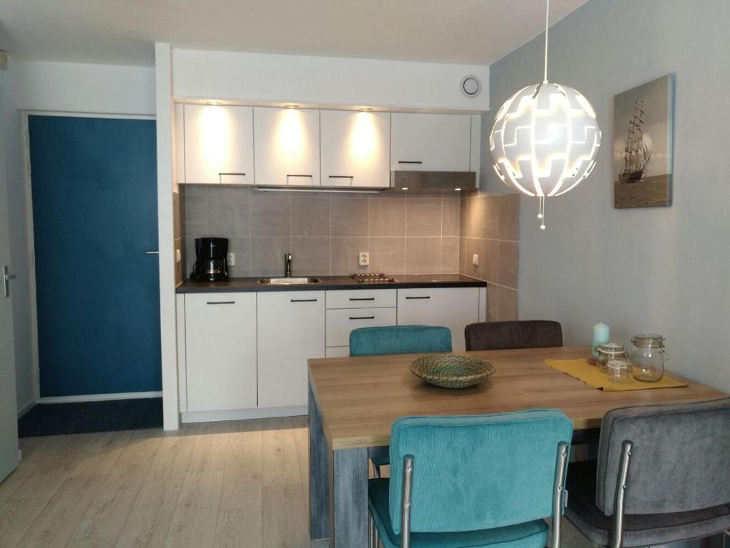 a kitchen with a wooden table and blue chairs at Zeebries in De Kaap 4 p in Hollum