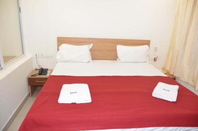 Un dormitorio con una cama roja con dos toallas encima. en Raya's Inn, en Kumbakonam