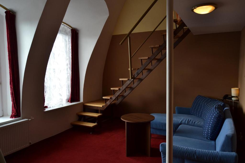a living room with a blue couch and stairs at Hotel Černý Orel Žatec in Žatec