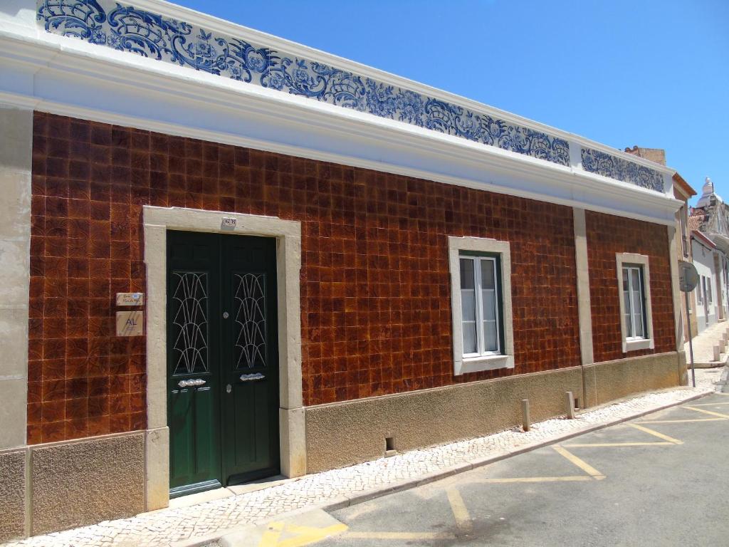 un bâtiment en briques rouges avec une porte verte dans l'établissement Casa Flor do Mar Lagos, à Lagos
