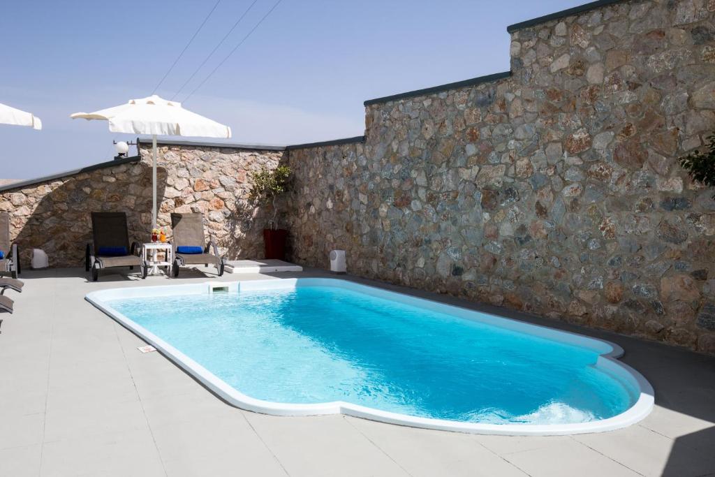 una piscina frente a una pared de piedra en Villa Libertad en Imerovigli