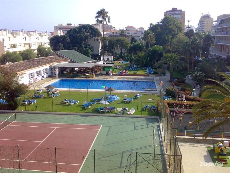 a pool with a tennis court and chairs on a court at Carihuela Park Palace - Cocasa in Torremolinos