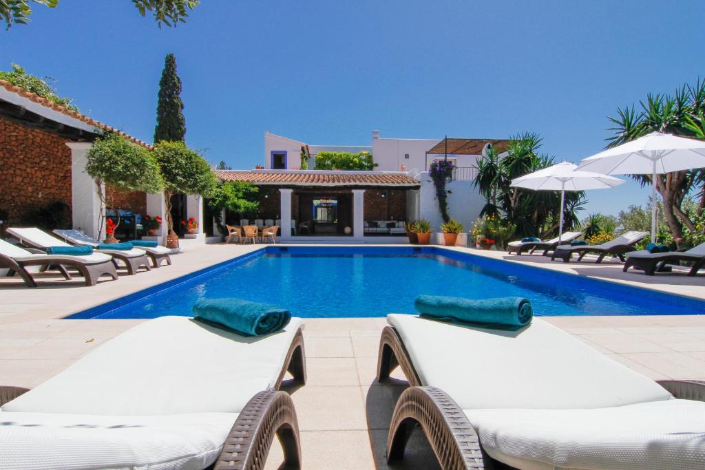 einen Pool mit Liegestühlen und eine Villa in der Unterkunft Bab el Oued Villa Ibiza in Puig D’en Valls