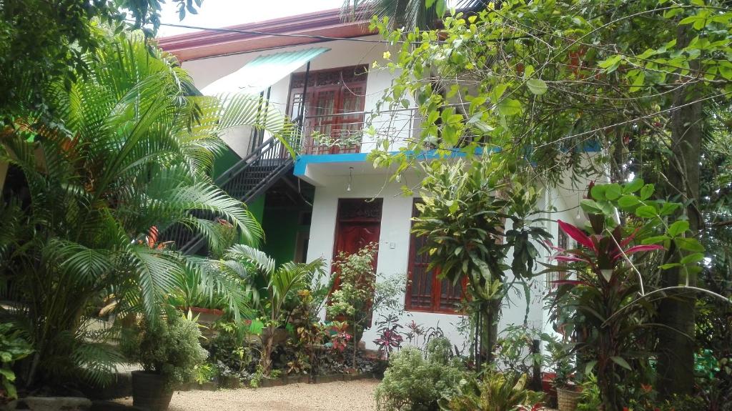 a white house with red windows and plants at Green Garden Homestay in Giritale