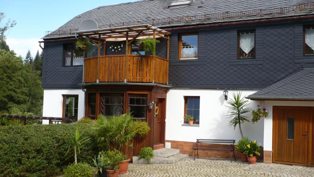 ein Haus mit einer Holzterrasse und einem Balkon in der Unterkunft Hammerfinken-Nest in Wurzbach