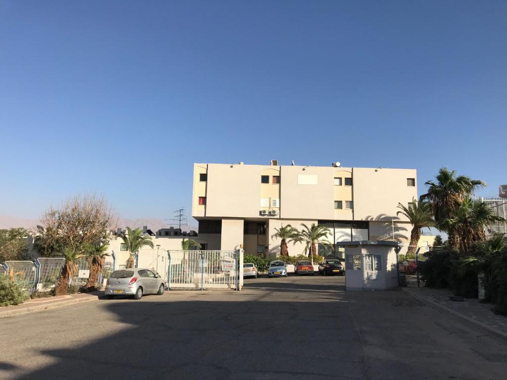 un grand bâtiment avec des voitures garées devant lui dans l'établissement Vacation Apartment, à Eilat