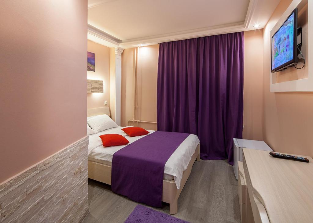 a hotel room with a bed and a purple curtain at Garden Hotel in Moscow
