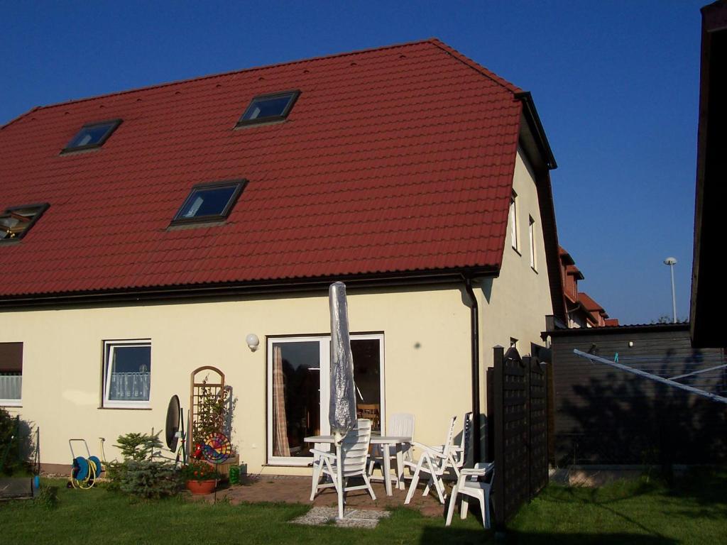 ein weißes Haus mit einem roten Dach sowie einem Tisch und Stühlen in der Unterkunft Haus Sonnenstein in Pirna