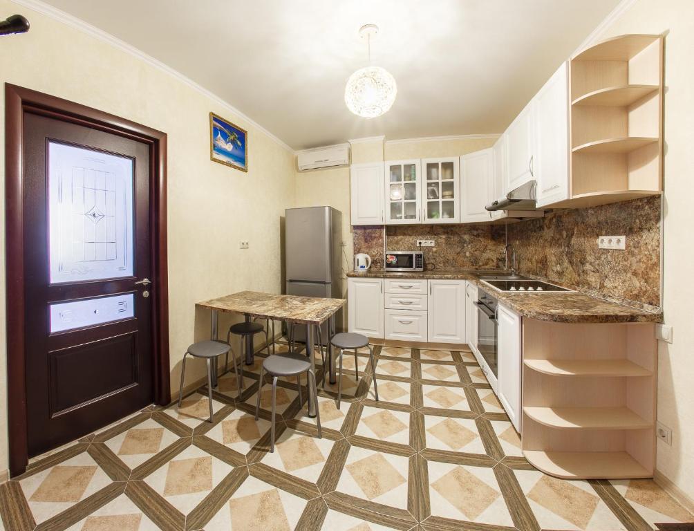 アナパにあるApartment on Tamanskaya 24の白いキャビネット、テーブルと椅子付きのキッチンが備わります。