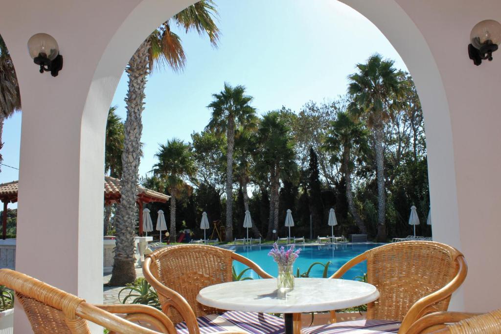 een patio met een tafel en stoelen en een zwembad bij Andromeda Hotel Apartments in Kos-stad