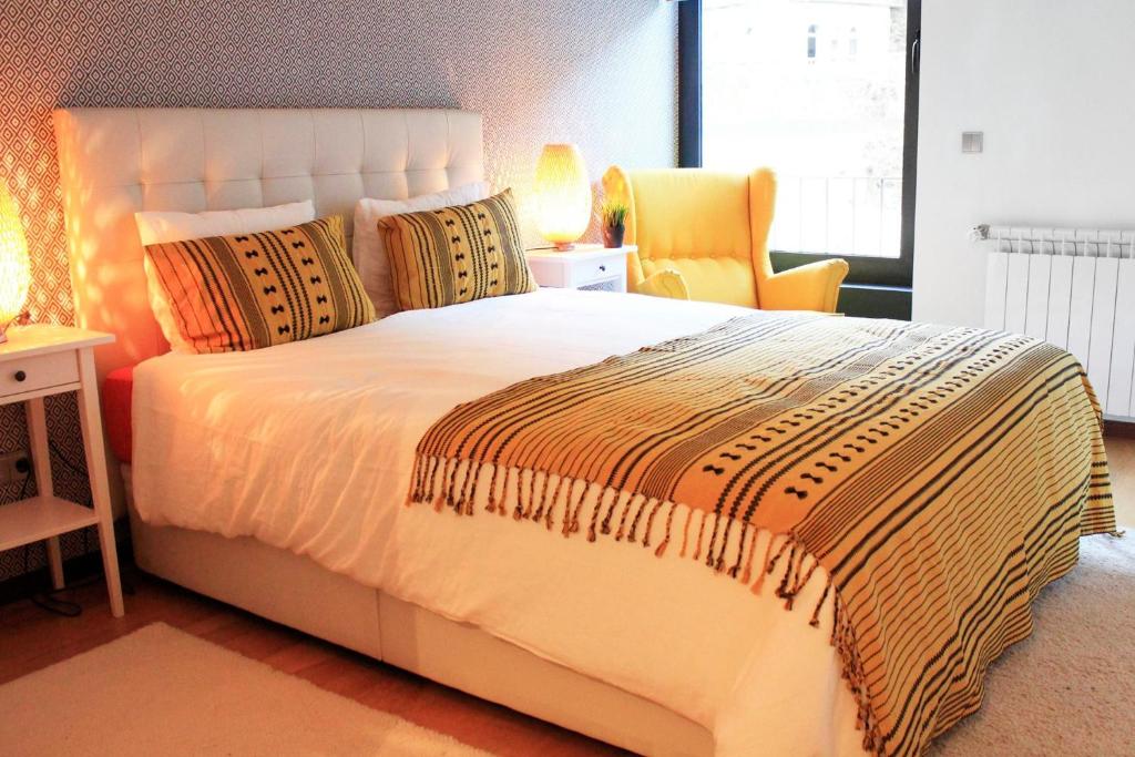 ジェレスにあるCaldas do Gerês Apartmentのベッドルーム(大きな白いベッド1台、黄色い椅子付)