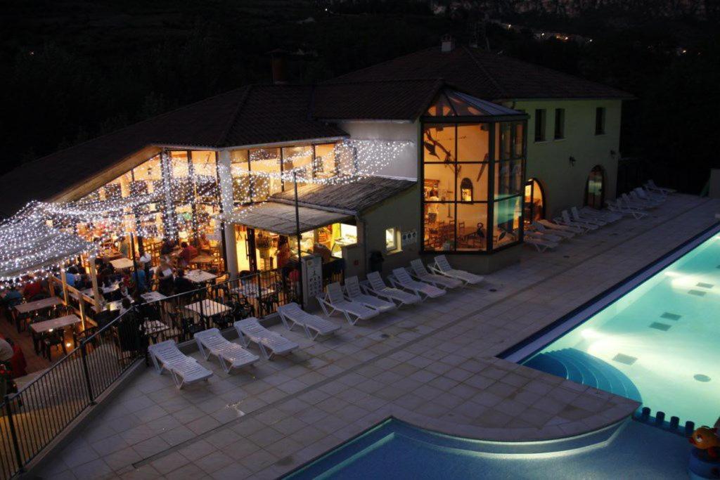 a resort with a pool and a restaurant at night at Camping Les Prades in Mostuéjouls