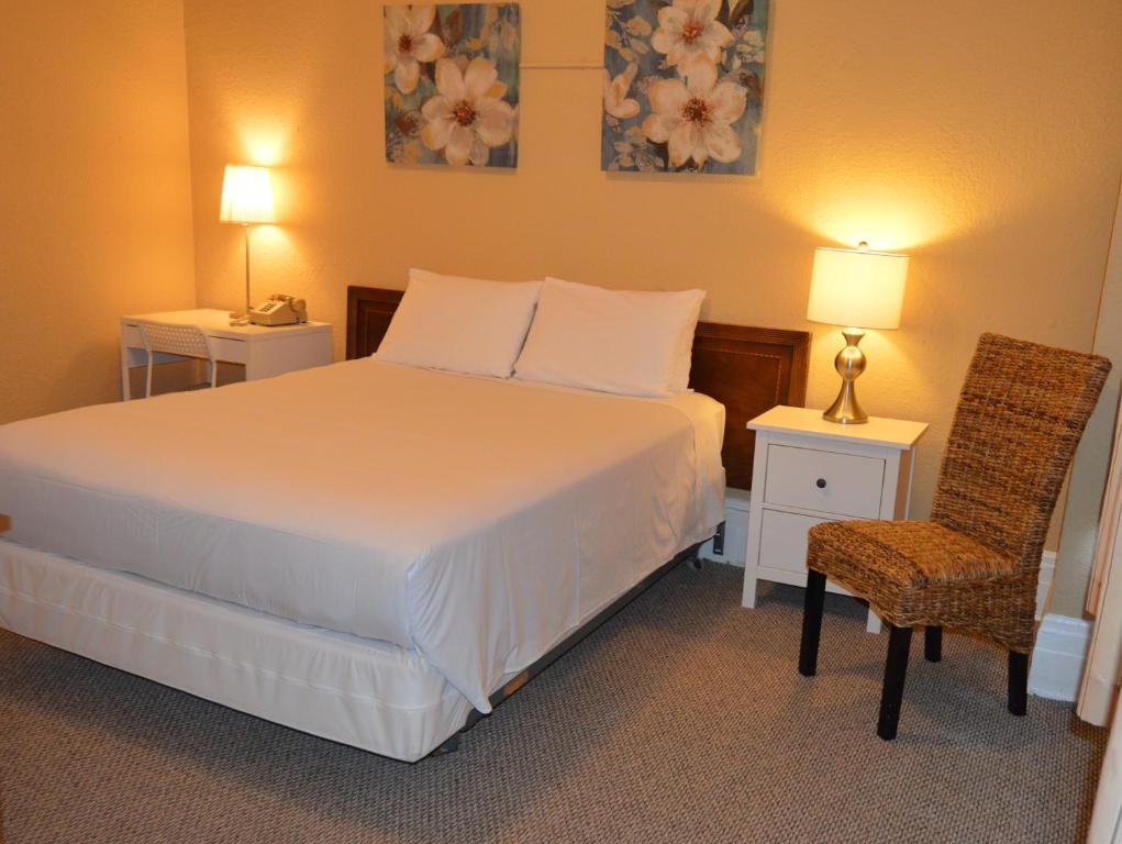 a bedroom with a bed and two tables and a chair at SF Plaza Hotel in San Francisco