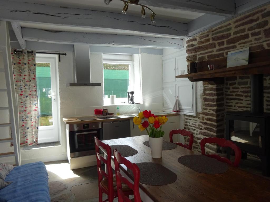 a kitchen with a table and chairs and a kitchen with a brick wall at La Cour du Bourg in Saint-Jean-des-Champs