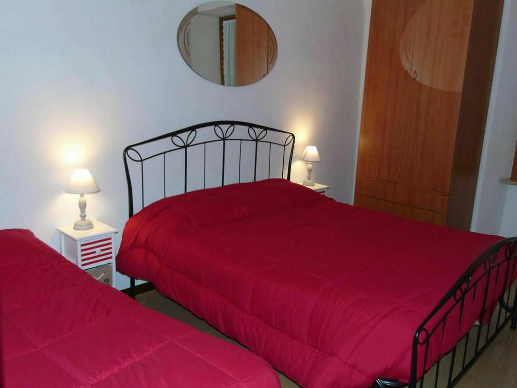 a bedroom with two beds with red sheets and a mirror at La casa sul mare in Riva Ligure