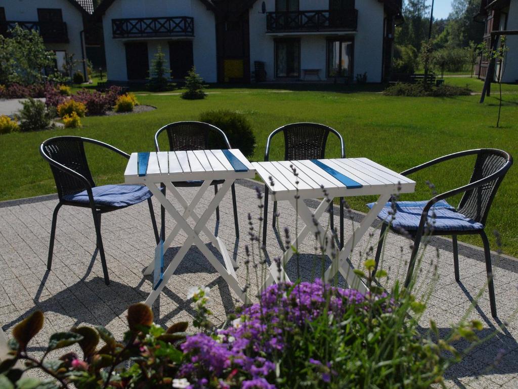 a white table and chairs in a yard with flowers at apt. ALTERNATYWA in Żarnowska