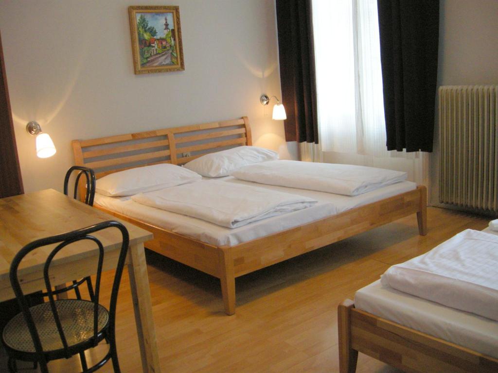 a bedroom with two beds and a table and a table and chairs at Pension Schottentor in Vienna