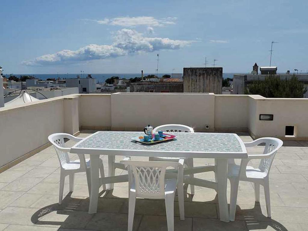 une table et des chaises blanches sur un toit dans l'établissement Panoramici Monolocali, à Leuca