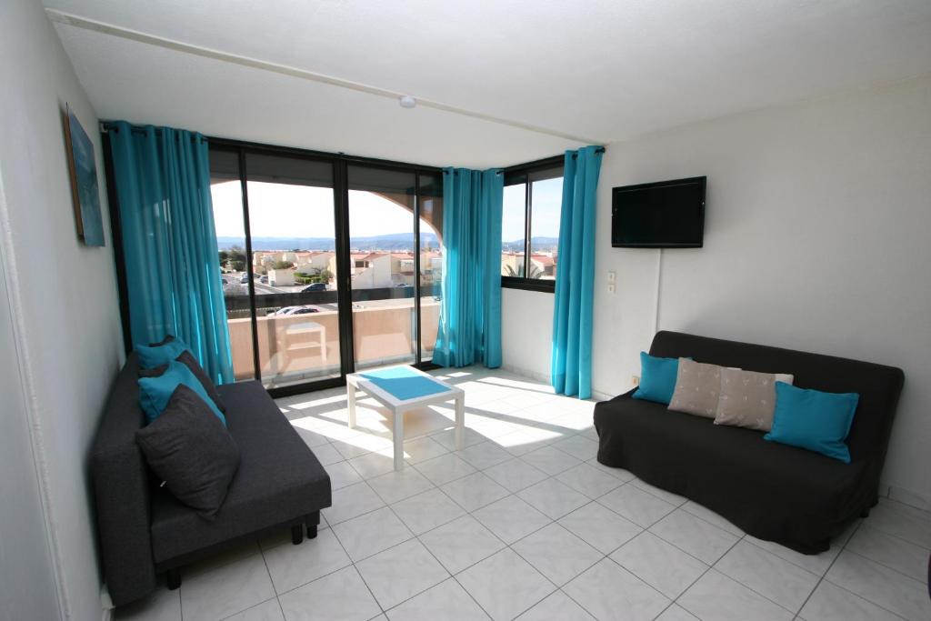 ル・バルカレスにあるFront de Merのリビングルーム(青いカーテン、ソファ、テレビ付)