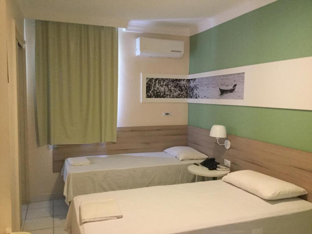 two beds in a room with green walls at Hotel Porto Grande in Maceió