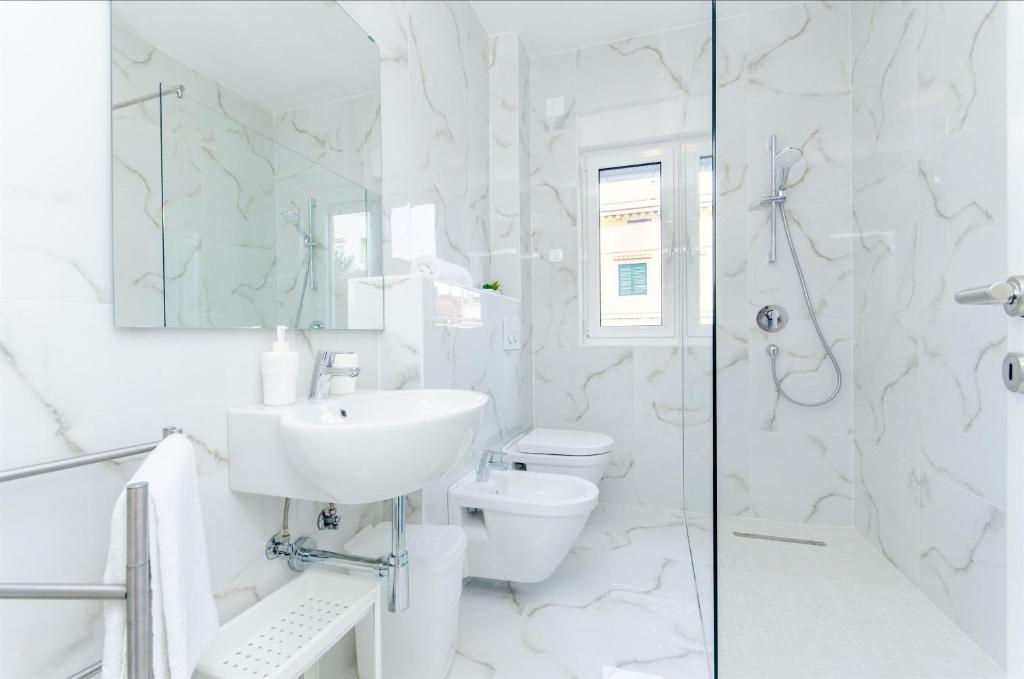 biała łazienka z umywalką i toaletą w obiekcie Apartments Branimir w mieście Mandre