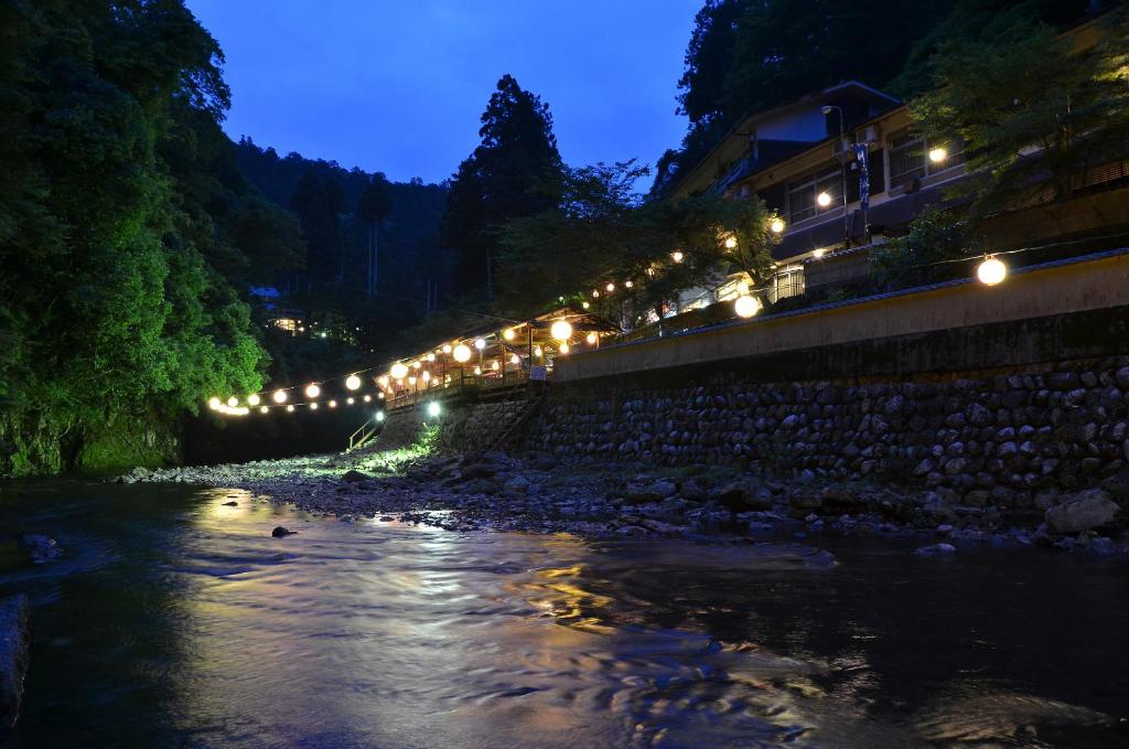 a river at night with lights on a bridge at Takao Kanko Hotel in Kyoto