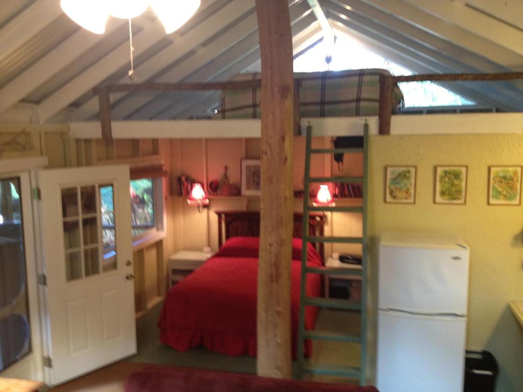 a bedroom with a bunk bed with a red bedspread at Carson's Kaloko Mountain Cabin in Kailua-Kona