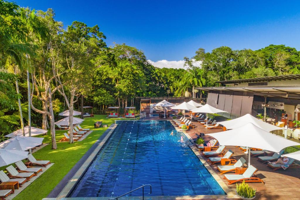 a swimming pool with several tables and umbrellas at Crystalbrook Byron in Byron Bay