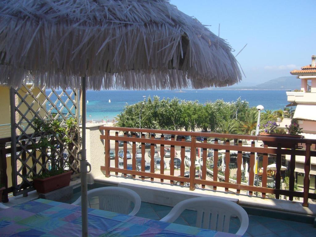 eine Terrasse mit einem Tisch, einem Sonnenschirm und dem Meer in der Unterkunft L'Ambra in Alghero