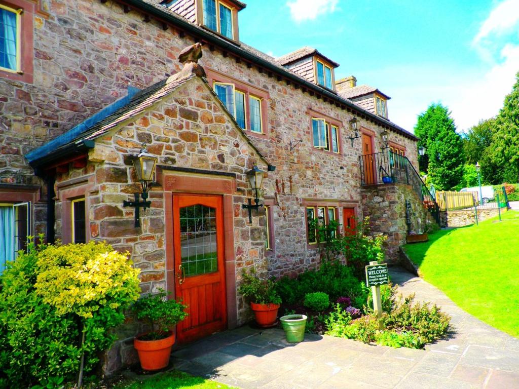 uma antiga casa de pedra com uma porta vermelha em The George Inn & Millingbrook Lodge Ltd em Lydney