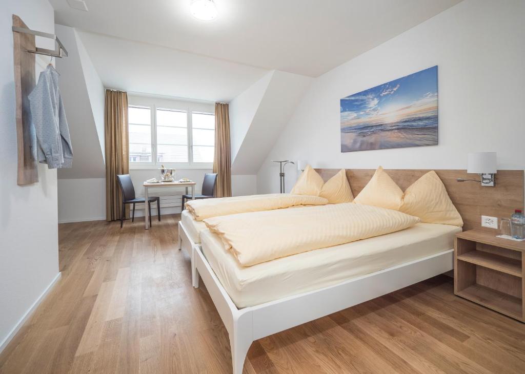 Dormitorio blanco con cama y mesa en Aparthotel Bären, en Seengen