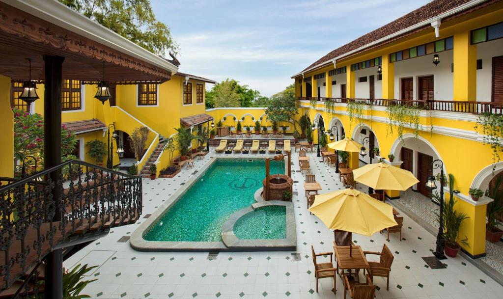 an outdoor pool with tables and umbrellas next to a building at Forte Kochi in Cochin