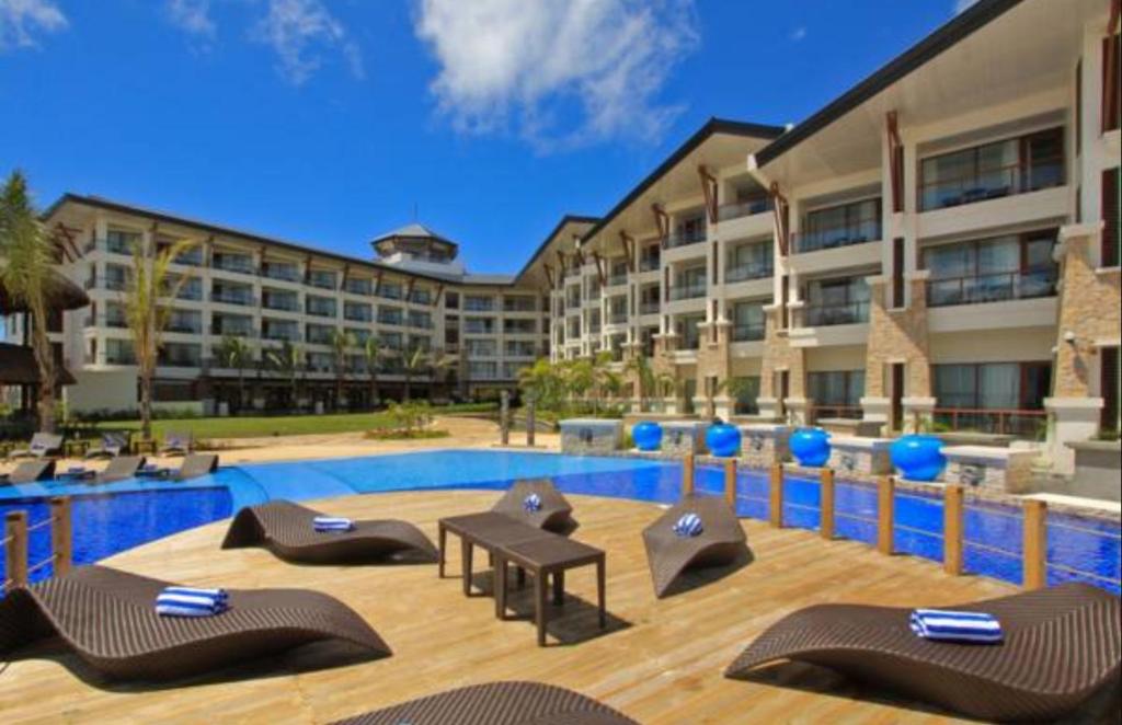 a resort with a swimming pool with chairs and a table at The Bellevue Resort in Panglao Island