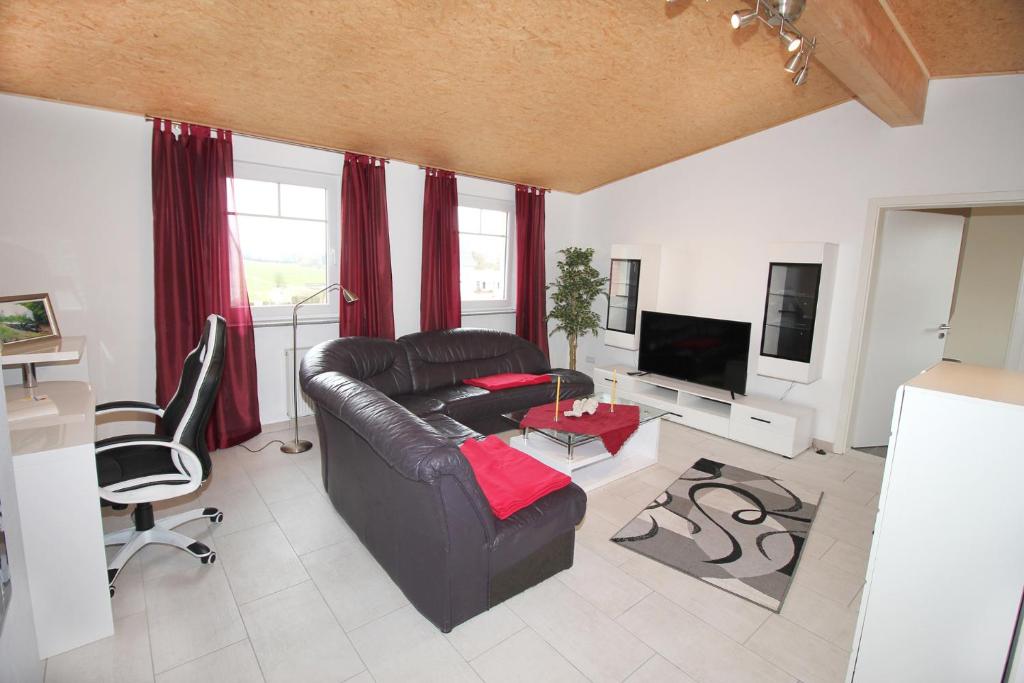 a living room with a leather couch and a tv at Ferienwohnung BECKENDORF in Losheim