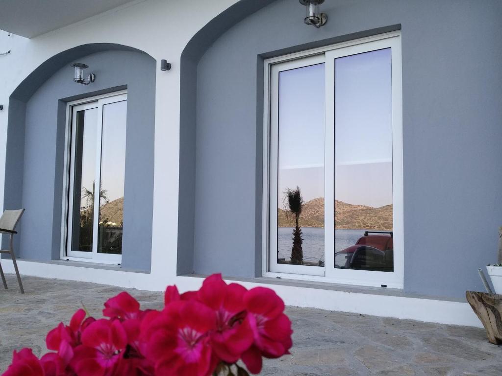 a room with three windows and a vase with pink flowers at Iliana Sea Side House in Elounda