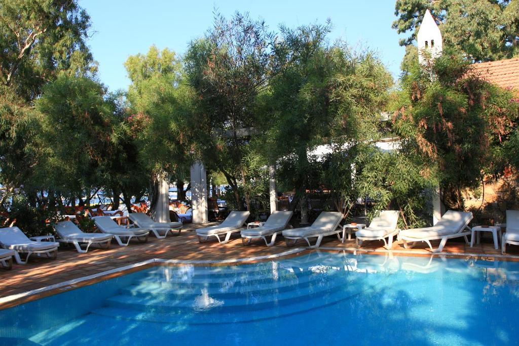 a swimming pool with lounge chairs and trees at Okaliptus Hotel in Bitez