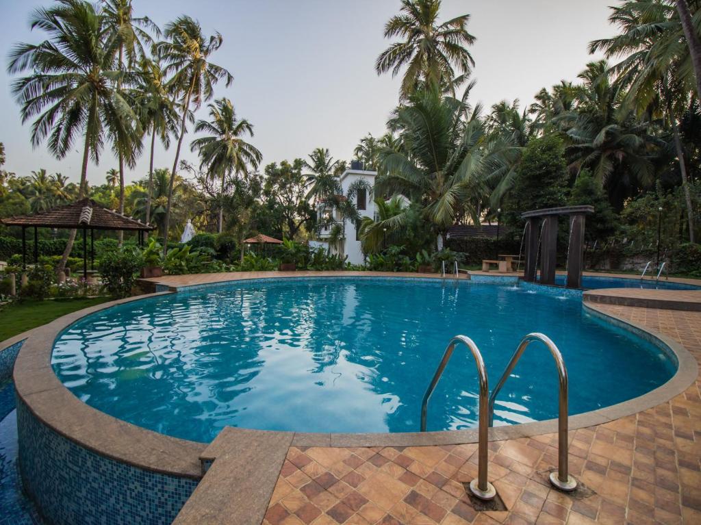 uma piscina num resort com palmeiras em Johnnie Holiday Homes em Arpora