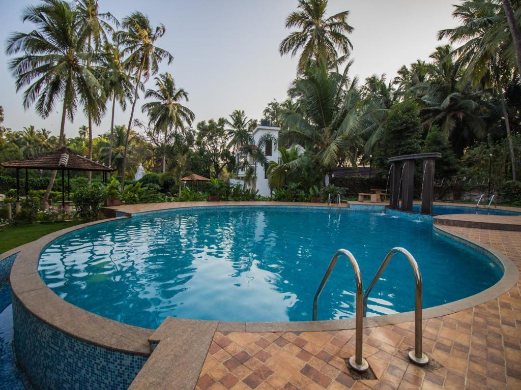 a swimming pool in a resort with palm trees at Johnnie Holiday Homes in Arpora